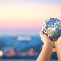Human hands holding earth global over blurred city night background. Elements of this image furnished by NASA